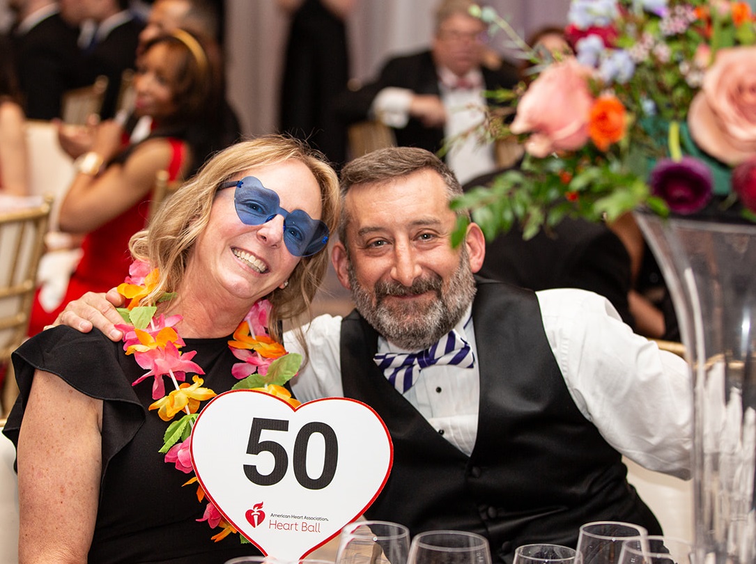 Couple at a table holding up bidder paddle number fifty.
